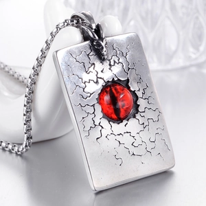 Vue macro d'un pendentif punk en acier avec oeil maléfique rouge et relief de dragon