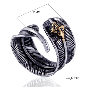 Macro detail of retro feather open ring in silver with a gold cross and size specs