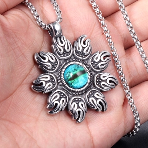 Macro detail of sun flame pendant with blue evil eye bead on stainless steel chain