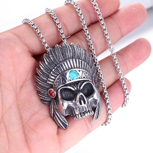 Vue macro du pendentif tête de mort avec couronne de plumes et incrustation turquoise