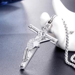 Close-up of a silver crucifix pendant with crystal pavé and JH engraving on a box chain