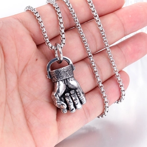 Detail shot of punk style stainless steel fist pendant on square box chain held in hand