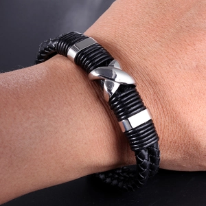 Detail of black woven leather bracelet featuring a polished silver X-shaped magnetic clasp