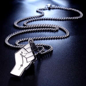 Macro shot of silver fist pendant with white fill and chain on dark background