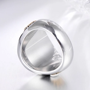 Macro detail of wide stainless steel ring featuring gold accents and black inlay stones