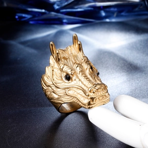 Macro shot of gold-plated dragon ring with intricate scale details and black stone eyes