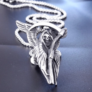 Detailed macro shot of vintage silver grim reaper pendant with scythe and wings