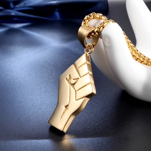 Macro shot of gold stainless steel fist pendant necklace on a hand display