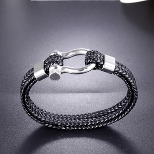 Macro shot of double-strand braided black leather bracelet with silver horseshoe buckle