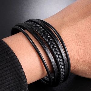 Gros plan d'un bracelet multicouche en cuir noir avec des textures tressées