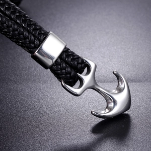Detailed macro view of silver stainless steel anchor clasp on braided black leather bracelet