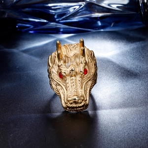 Macro view of a gold dragon head ring with detailed scales and red rhinestone eyes