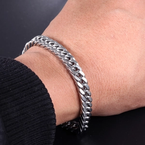 Men's silver stainless steel Cuban link bracelet styled with a black sweater