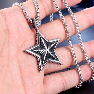 Macro detail of a vintage star pendant with black-oxidized texture and box chain