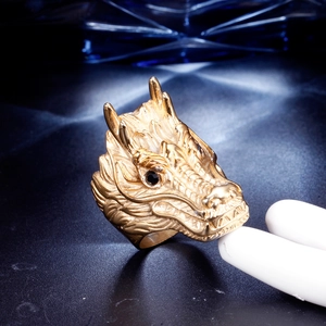 Detailed close-up of a dragon head ring with gold scales and black stone eye