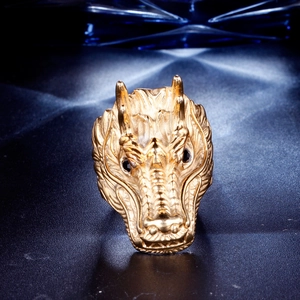 Detailed close-up of golden dragon head ring with intricate scales and black stone eyes