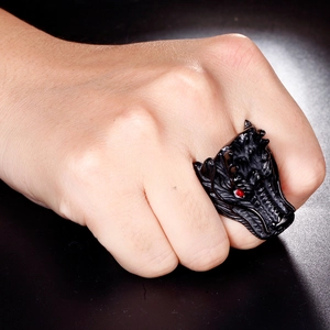 Close-up of matte black dragon head ring with red gemstone eyes on male hand