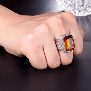Close-up of vintage steel ring with amber rectangle gemstone and vine engravings