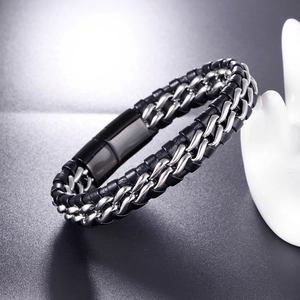 Détail du bracelet tressé en cuir noir et chaîne en acier avec fermoir métallique