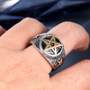 Men's vintage titanium steel ring with a golden pentagram star on hand with blue background