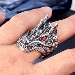 Detailed close-up of a dragon head ring in vintage silver with red zircon eyes on a hand