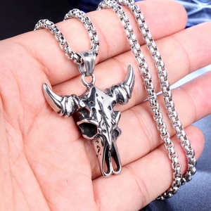 Close-up of vintage bull skull pendant necklace with chunky chain held in palm for size