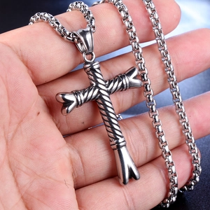 Detailed close-up of a rustic silver cross pendant with twisted rope texture on a box chain