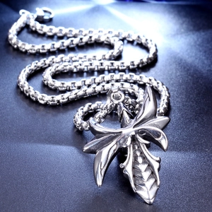 Detailed close-up of retro gothic cross pendant with intricate wings and antique texture