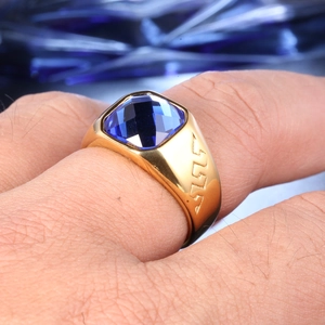 Detailed shot of a gold ring with a square blue gemstone and Greek meander engraving