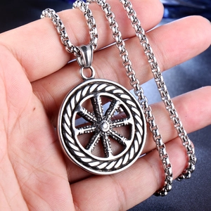 Detail of vintage silver dharma wheel pendant on box chain with intricate metal texture