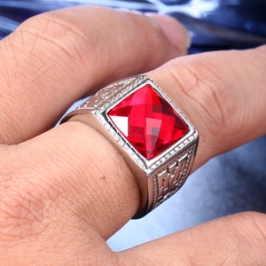 Macro shot of silver ring with square red gemstone and geometric side engravings