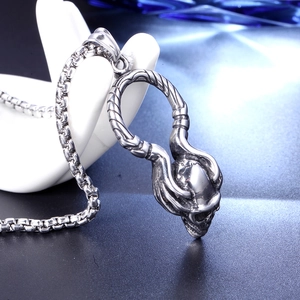 Détail d'un pendentif tête de mort argenté avec chaîne box sur fond sombre