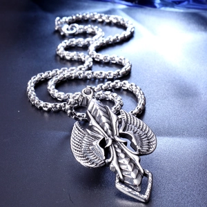 Close-up of gothic stainless steel wings pendant with vintage relief on dark background