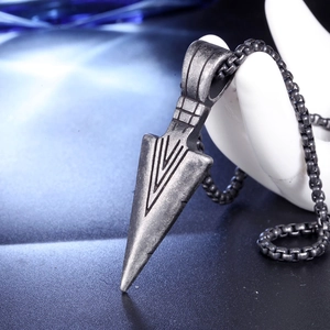 Close-up of vintage oxidized stainless steel arrow pendant with engraved geometric lines