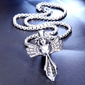 Macro shot of gothic stainless steel wings and heart pendant on a metal chain