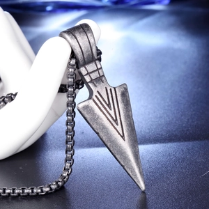 Macro view of vintage stainless steel arrow pendant with engraved lines on a box chain