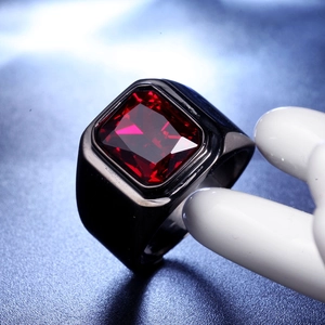 Gros plan d'une bague large pour homme en acier noir sertie d'un zircon rouge rectangulaire
