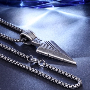 Macro shot of vintage arrow pendant with box chain on black leather background