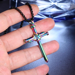 Détail du pendentif croix en clous d'acier inoxydable arc-en-ciel sur chaîne noire