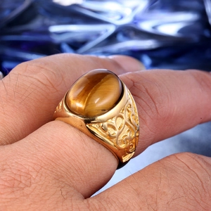 Macro view of men's gold stainless steel ring with oval tiger eye stone and filigree detail