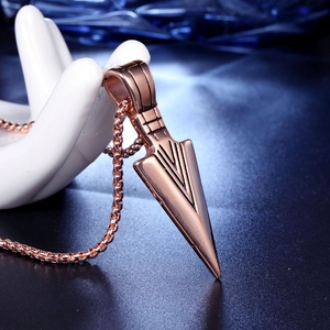 Macro view of a rose gold arrow pendant necklace with textured detail on a ceramic hand model