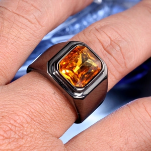 Gros plan d'une bague pour homme en métal gris avec pierre ambre rectangulaire