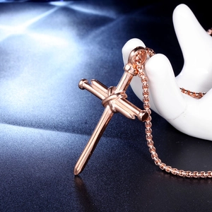Collier avec pendentif croix en acier inoxydable or rose sur support de main en céramique