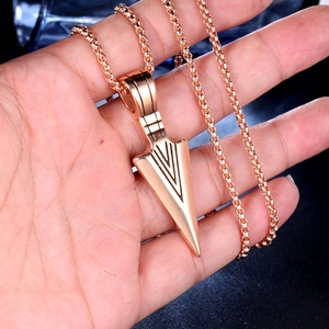 Close-up of rose gold arrowhead pendant with box chain held in hand on black background