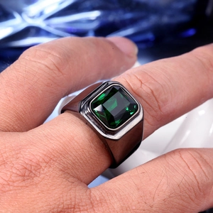 Gros plan d'une bague large pour homme en acier inoxydable avec une grande pierre verte émeraude