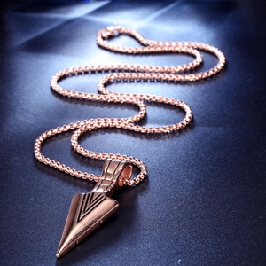 Detail of rose gold arrowhead pendant with geometric texture and industrial chain