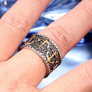 Macro detail of men's vintage punk anchor ring with gold accents on textured metal