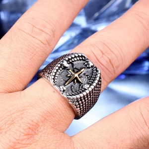 Macro shot of vintage steel compass ring for men with gold star and engraved directions