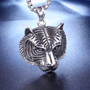 Detailed relief of vintage silver tiger head pendant on a textured blue display surface