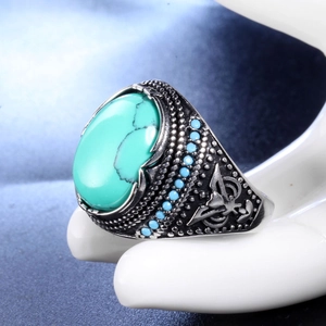 Gros plan d'une bague hip-hop dorée avec turquoise ovale et gravures tribales